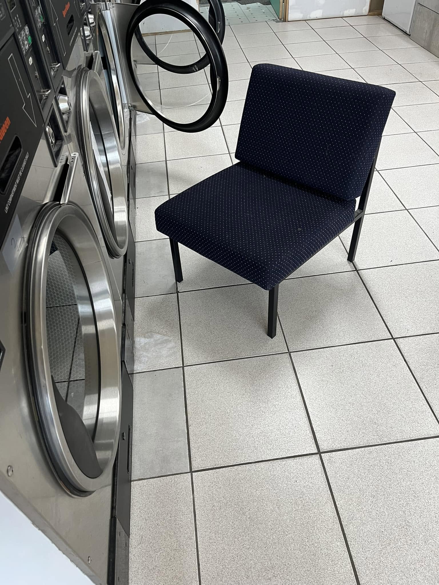 Row of commercial washing machines and dryers inside Melba Laundrette